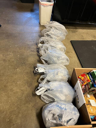 a large group of donated food items in plastic bags on the floor