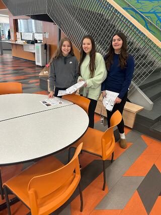 3 female students smiling at table