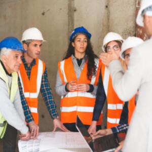 A group of people with hard hats looking at construction plans